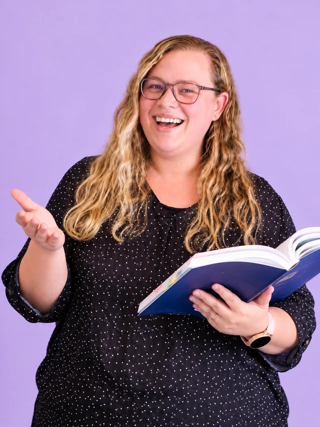Monique Fourie holding an open book with one hand held out in welcome