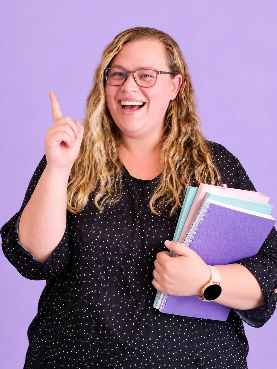 Monique Fourie holding her notebooks and pointing upwards with a big smile